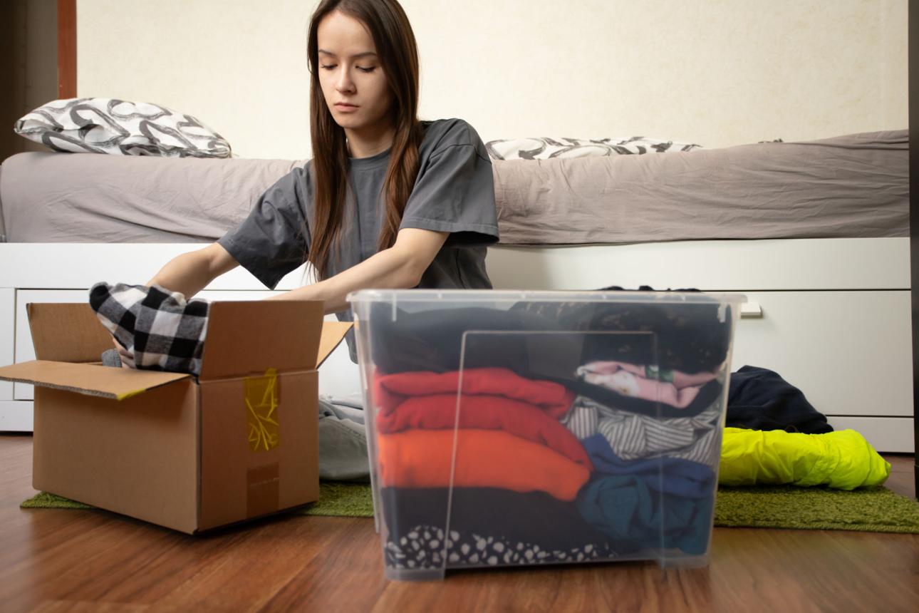 Student packing books, clothes and kitchen utensils for study abroad shipment from India